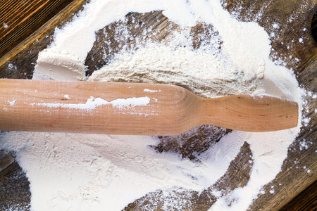 a wooden rolling pin and white wheat flour used during cooking baking at homeの写真素材