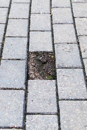 made of slabs road, one of which broke and appeared pit, closeup