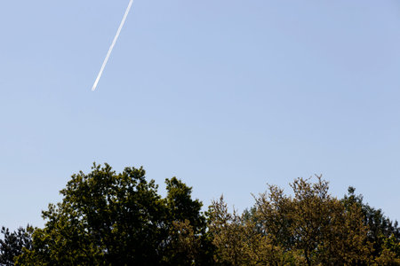 an inversion trail from a flying plane against a blue sky, sunny clear weather, the technique left...
