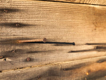 old metal nail with rust hammered into old wooden boards when building in a barn village, closeupの写真素材