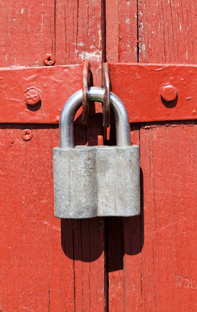 steel metal padlock on a wooden door in red paint, closeup