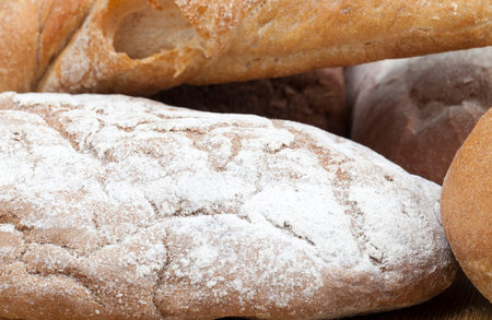 sprinkled with white wheat flour loaf of fresh bread baked from different types of flour, closeup