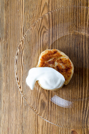 ready and delicious stuffed cottage cheese with sour cream, closeup meal on a transparent plate of glass, which lies on an old wooden table, photo from the topの写真素材