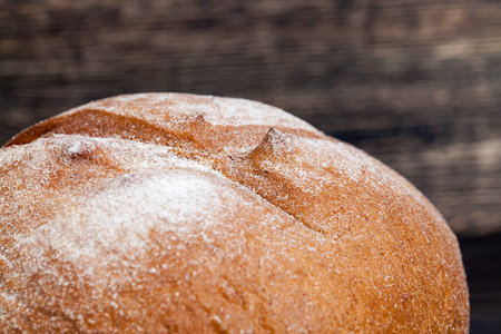 fresh round rye bread lying after baking on a black wooden table