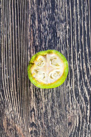 a roughly broken and chopped green walnut with an unformed fruit, half of the nut shows its future...