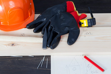 Pencil, pine board, gloves and a construction orange helmet, and a birdhouse drawing that will build