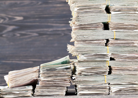 A tower with a lot of paper money and a broken staircase of small bundles with bills, closeup