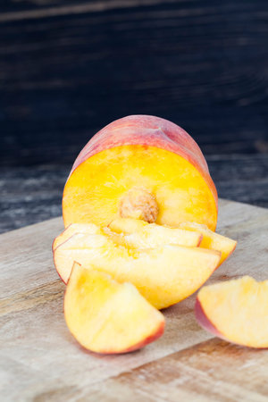 Cut into pieces ripe peach during the preparation of sweet dessert with fruit