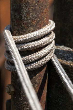 Old rusty and oxidized pipe to which the ropes are tied