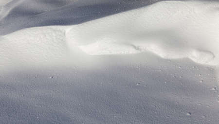 beautiful uneven snowdrift of pure snow, illuminated by sunlightの写真素材