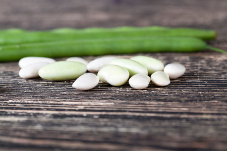 green fresh pods and mature white bean seeds on the table