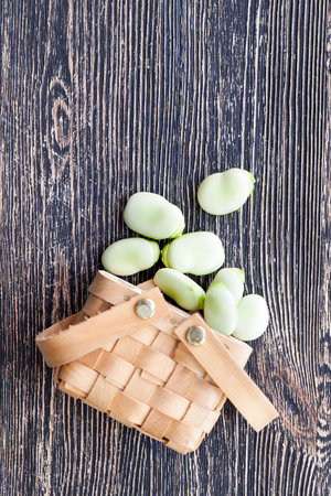 lying in a roughly made wooden basket a number of beans, on a wooden table