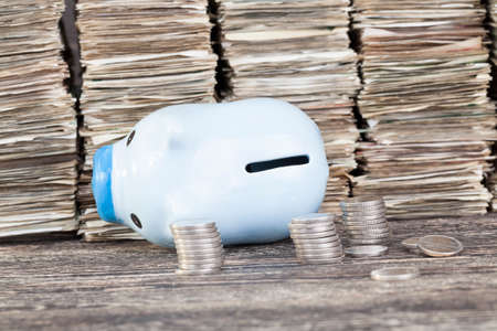 folded old tattered banknotes in a large level tower, close-up, before the money lies a pig piggy bank in focus, and silver coins are out of focusの写真素材