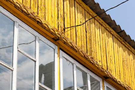 Part of the old long-painted yellow paint building with power wiresの写真素材