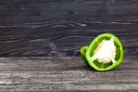 cut into half one pepper green, closeup on a black board with a black wall, kitchen areaの写真素材