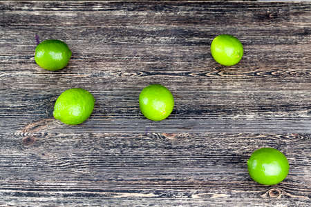 chaotically scattered on the table green ripe sour limes, black backgroundの写真素材