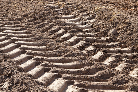 traces of the protector of a heavy large car on the dried field soil, closeup