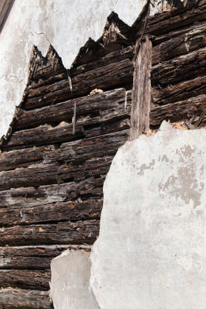 broken plaster on an old building of wooden logs, which began to rot and break, closeupの写真素材