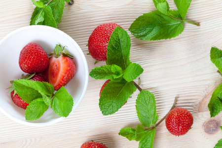 red delicious strawberries and green leaves of fragrant mint while preparing dessertの写真素材