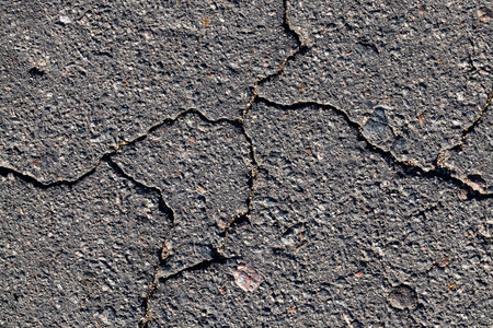a large number of cracks on the dark asphalt road, details of the transport infrastructure