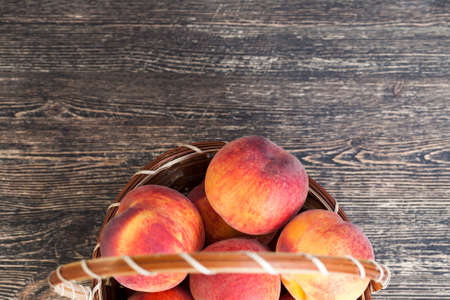 basket of ripe red and juicy peaches, on a black table in the kitchenの写真素材