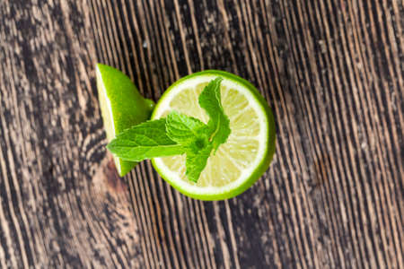 sliced lime green and a few mint petals against a black table, top viewの写真素材