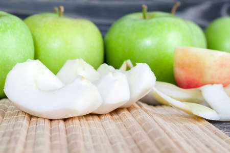 sliced green juicy and ripe apple used to make fruit dishes and desserts, a few apples are wholeの写真素材