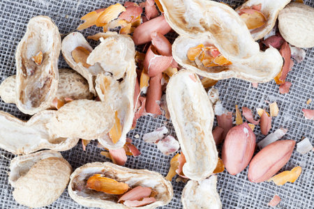 broken and peeled peanuts with shells, edible part without shells and ready for ingestion, lies a...