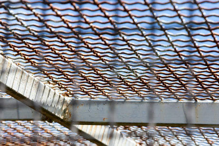 Old metal cage close up against a blue sky, on the metal there are signs of rust and damage