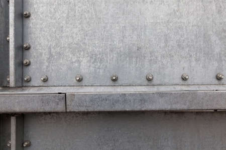 part of a metal barrel connected from metal sheets with bolts and rivetsの写真素材
