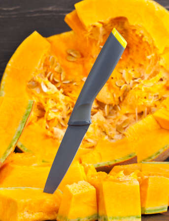 Sliced diced and other forms of ripe orange pumpkin during cooking and food, closeup in the kitchenの写真素材