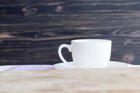 tablecloth is an empty white porcelain mug, in front of the mug is a wooden cutting boardの写真素材