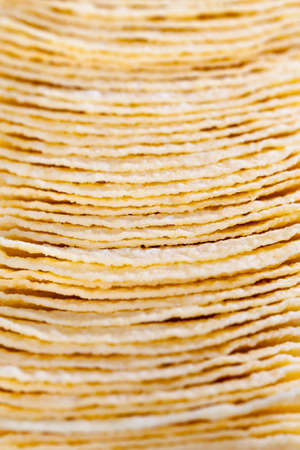 light-colored thin potato chips made from mashed potatoes, natural to the harmful product on the tableの写真素材