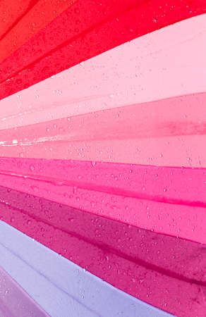 multicolored umbrella covered with drops of water from rain past or walking, closeup useful items, trendy lookの写真素材