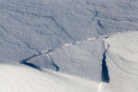 A large beautiful snowdrift of snow, part of which was destroyed under its own weight after snowfall, close-up in the frosty winterの写真素材