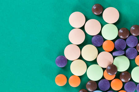Multi-colored pills on a green background of various packs, a bunch of drugs on paper, medical treatment helpの写真素材