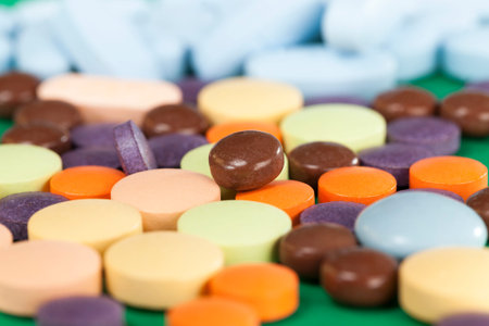 Multi-colored pills on a green background of various packs, a bunch of drugs on paper, medical...