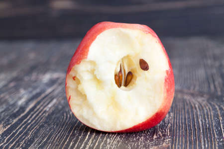 bitten off a piece of red ripe apple with black bones, closeupの写真素材