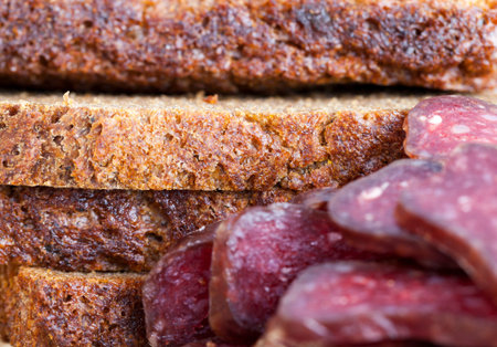 Home-made red meat sausage sliced with bread in the kitchen while preparing a large number of snacks for the holidayの写真素材