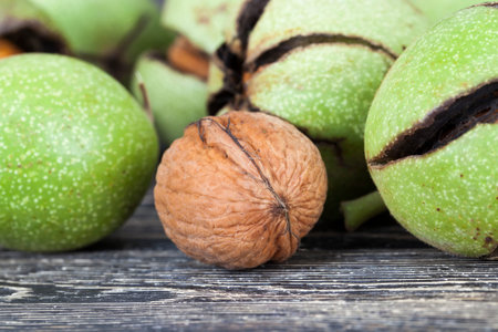 broken ripe walnuts in early autumn or late summer, lie on a wooden floor after receiving the...