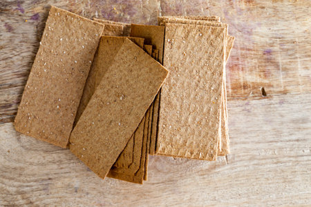 Thin rye crispy crackers lying on a wooden cutting board in the kitchen, Food Rich in fiber
