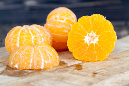 The cut peeled mandarin on the cutting board, juice spreads to the board