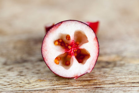 Cut half-ripe cranberries, on the wooden , inside the berries are visible small seeds