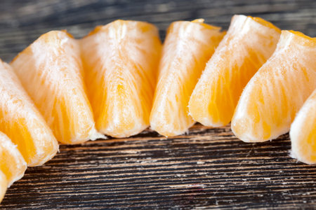 mandarin slices put in a row from ripe orange citrus fruit, sliced into slices, on a wooden surface