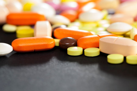 A large number of multi-colored tablets and pills lying together in a chaotic manner. scattered on...