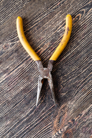 Old pliers lying on an old wooden black board, a tool for construction and repairの写真素材
