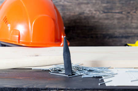 Several construction tools on a black chalkboard helmet hammer nails note paperの写真素材