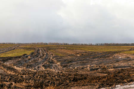 field after the rain by which drove large, heavy vehicles. Footprints and a deep rut in the ground. Photo in the autumn seasonの写真素材