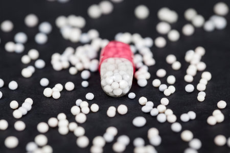 medical capsule with the drug inside, on a black paper background, around the capsule the contents...