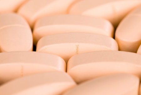 convex light-colored pills unpacked lying in a heap, close-up of medical drugs